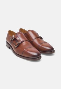 Braune Leder-Doppel-Monk-Strap-Schuhe mit polierter Oberfläche, gebogenem Zehenbereich und dekorativen Nähten. Mit zwei metallischen Schnallen-Verzierungen.