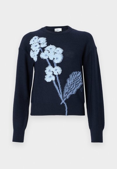 Tums zila džemperis ar garām piedurknēm un ribotu apakšu, rotāts ar gaiši zilu ziedu izšuvumu priekšpusē.