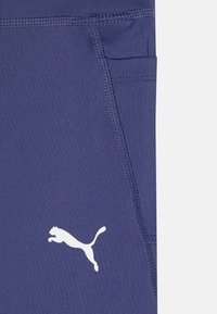 Calças de atletismo azul marinho feitas de tecido elástico, com um bolso lateral e o logótipo branco da Puma. As características incluem costuras planas e uma textura suave.