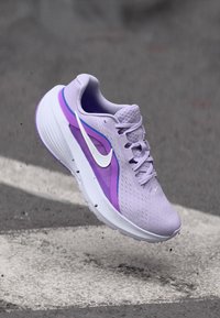 Μωβ αθλητικό παπούτσι με αναπνεύσιμη επάνω επιφάνεια από δίχτυ, λογότυπο λευκό swoosh, μωβ και μπλε λεπτομέρειες, και μαλακή σόλα.