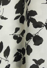 Černý květinový vzor na bílém plátně, zobrazující tvary listů s hladkou texturou a jemným leskem. Vzor je na materiálu opakovaný.