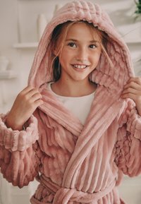 Roosa pehme hommikumantel tekstuurse kapuutsi ja varrukatega. Omab mähisdisaini ja vööd, näidates pehmet, kohevat kangast ning soonilist detaili.