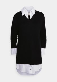 Maglione nero lavorato a maglia con scollo a V, dotato di maniche lunghe e polsini di camicia bianchi che spuntano dal fondo. Design stratificato con bottoni.