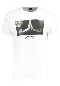 White cotton t-shirt featuring a black-and-white graphic of hands in prayer, with "pray" printed below in a cursive font. Short sleeves.