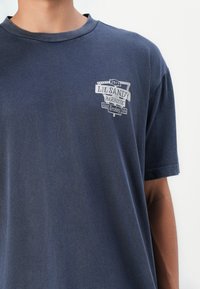 Navyblå bomull T-shirt med grafiskt tryck "Lil Sandy Barbecue" i vitt, rund hals och korta ärmar.