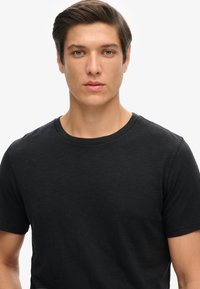 Zwarte crew-neck t-shirt van zachte stof, met korte mouwen en een relaxed fit, ontworpen voor comfort en veelzijdigheid.