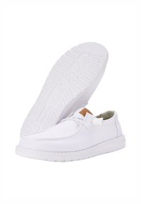 Scarpe da ginnastica bianche in tela con texture liscia, punta rotonda e suola in gomma. Presentano dettagli beige sulla linguetta e un design con lacci.