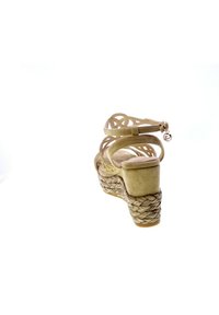 Sandalo wedge in suede beige con zeppa in juta intrecciata, apertura sul retro, dettagli decorativi sui cinturini e un piccolo charm metallico sul cinturino della caviglia.