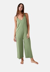 Mono verde sin mangas con escote en V, pantalones amplios y tirantes anudados. Fabricado con un tejido suave de textura lisa.