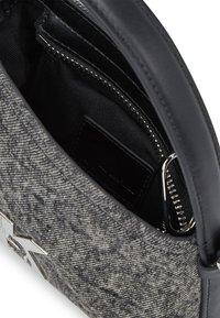 Γκρίζα υφασμάτινη τσάντα χειρός με μαύρη δερμάτινη λαβή, διαθέτει κλείσιμο με φερμουάρ, μαύρο εσωτερικό και ασημένια λεπτομέρεια με το λογότυπο.