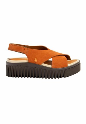 Sandalia naranja de punta abierta con suela negra gruesa y acanalada, tiras cruzadas, correa en el tobillo con velcro y pequeño detalle de flor en el lateral.