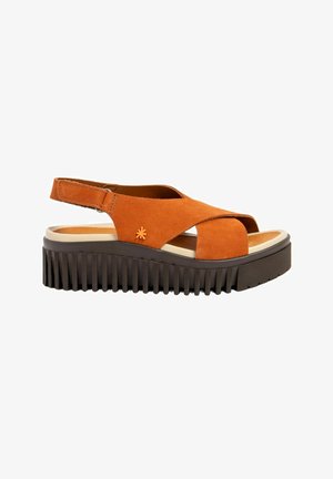 Sandalia naranja de punta abierta con suela negra gruesa y acanalada, tiras cruzadas, correa en el tobillo con velcro y pequeño detalle de flor en el lateral.