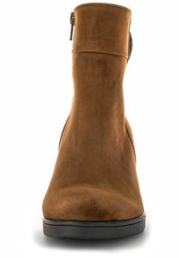 Bottine en suede marron avec un bout rond, texture lisse, fermeture éclair à l'intérieur et un petit talon en caoutchouc noir.