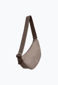 Bolso bandolera color topo con forma de media luna, correa ancha ajustable y detalle de logo frontal sobre un fondo blanco liso.