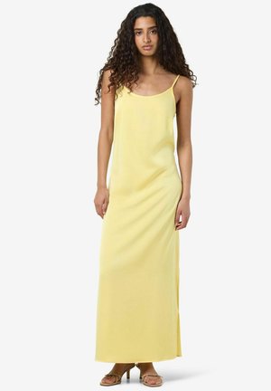 Vestido maxi amarillo con tirantes finos, hecho de una tela suave. Presenta un ajuste relajado y una abertura lateral para facilitar el movimiento.