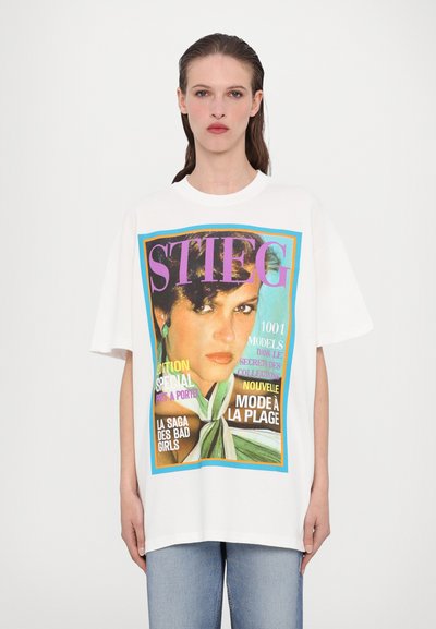 Fehér, túlméretezett póló, színes magazinborító grafikával, különböző betűtípusú szövegekkel, főként rózsaszín és kék színekben.