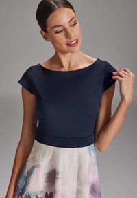 Haut ajusté bleu marine avec des manches courtes, se transformant en une jupe plissée ornée d'un motif floral dans des couleurs pastel avec de fines rayures.