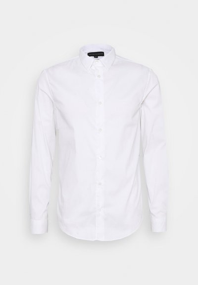 Balta ilgomis rankovėmis marškinių su mygtukų apykakle, pagaminti iš lygaus medvilninio audinio, su mažos logotipo ant krūtinės ir mygtukais priekyje.