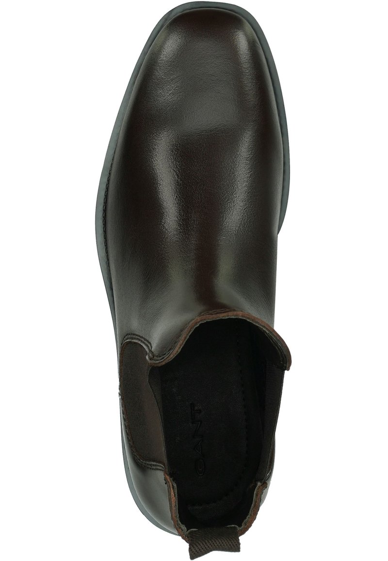 Bottine en cuir marron avec une finition lisse, des panneaux latéraux élastiques et un embout arrondi. Présente une semelle noire contrastante et des accents cousus.