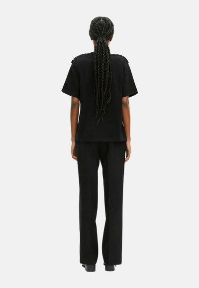 Conjunto negro que incluye una blusa holgada con detalles en los hombros y pantalones de pierna ancha a juego. Textura suave y diseño sencillo.