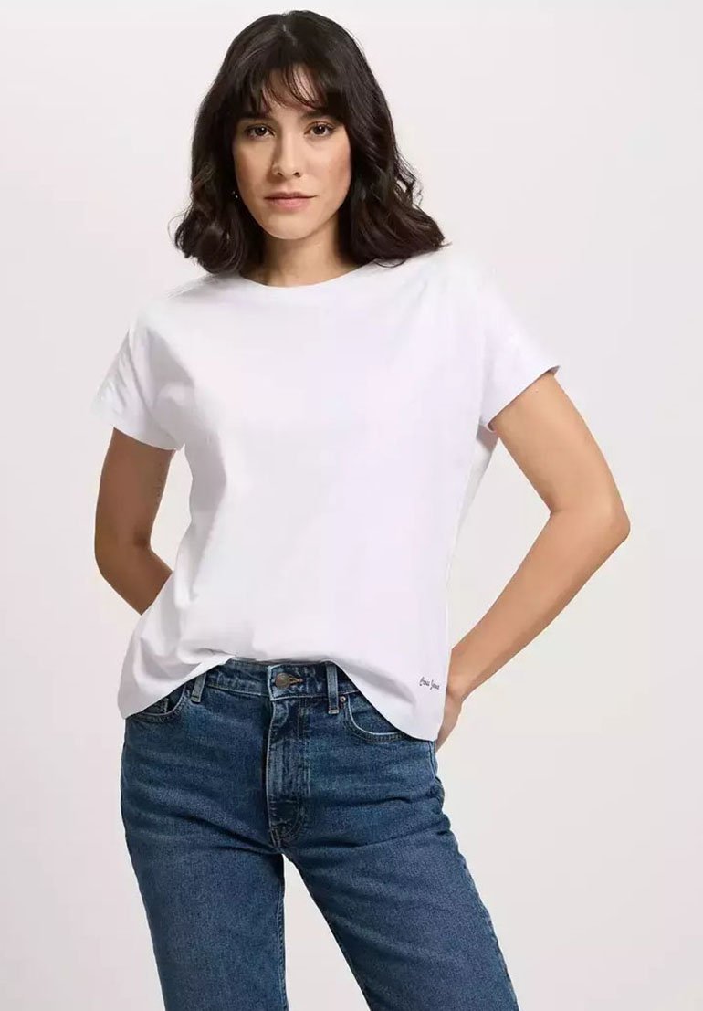Biała bawełniana koszulka z krótkim rękawem z klasycznym okrągłym dekoltem; luźny fason; z małym, subtelnym logo na dole po lewej stronie. W zestawie z niebieskimi dżinsami.