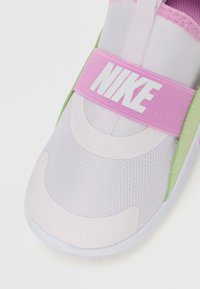 Valge ja helesinine Nike'i spordijalats, millel on esmase kihtvõrk ja roosa rihm keskjala ümber, millel on valge Nike'i logo.