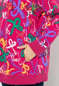 Felpa fucsia con stampa a nastro multicolore, tasca a marsupio, polsini a coste e cappuccio con cordino per una vestibilità regolabile.