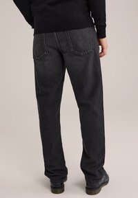 Donker gewassen denim jeans met een rechte pasvorm, voorzien van een vijfzakkenontwerp en subtiele stiksels op de achterzakken.