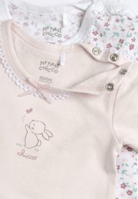 Bodysuit à manches courtes en rose pâle avec un graphique de lapin, des broderies en dentelle et une couche blanche à motifs floraux en dessous ; fermetures à pression sur les épaules.