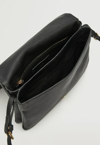 Borsa a mano in pelle nera con una texture liscia, scomparto principale con zip e una tracolla corta. L'interno è foderato in tessuto nero. Dettagli in metallo dorato.
