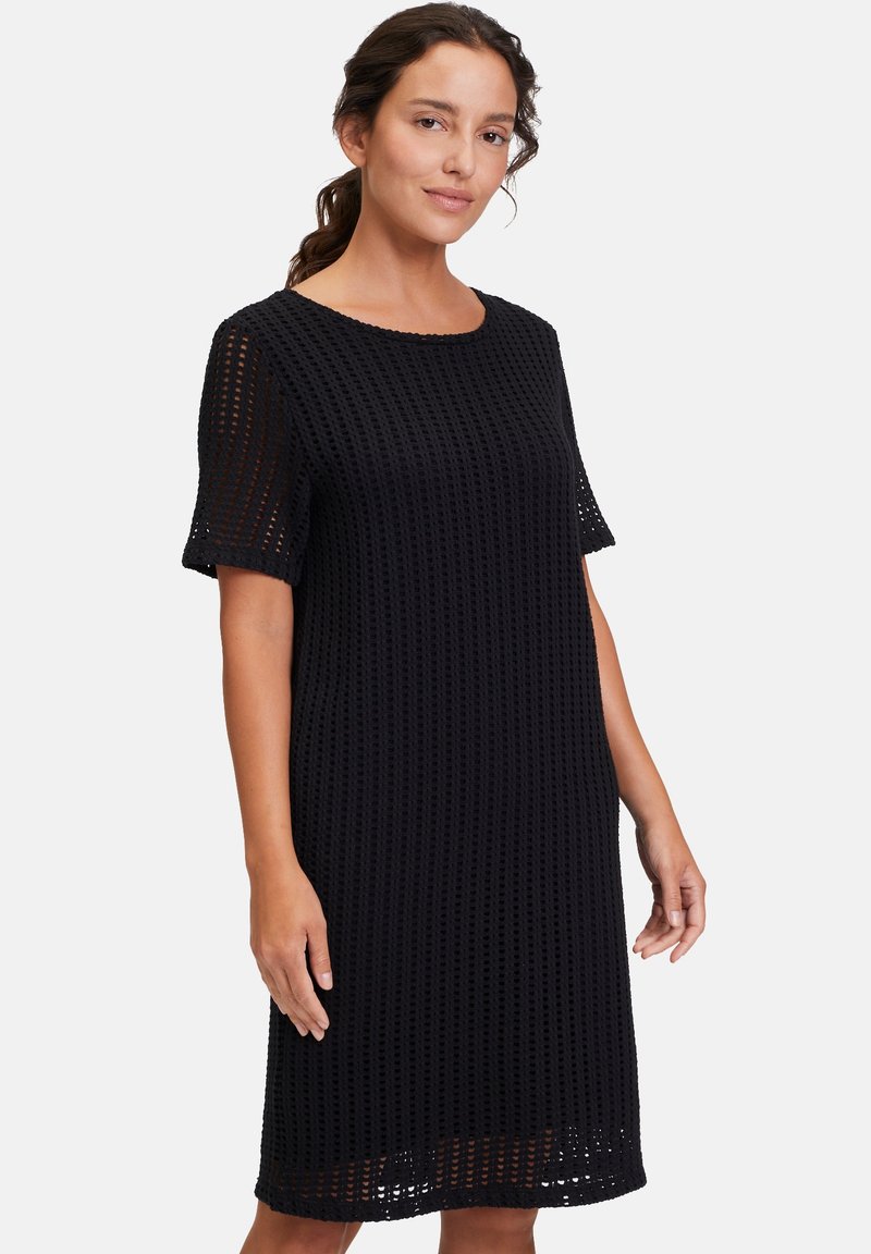 Schwarzes, gestricktes Kleid mit kurzen Ärmeln; zeichnet sich durch eine lockere Passform und ein Wabenmuster für Textur aus; runder Ausschnitt und knielanger Saum.