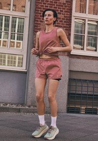 Pink athletic tank top and shorts with adjustable drawstring, paired with green sneakers and white crew socks. Smooth fabric, casual fit.