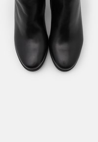 Black leather ankle boots with a smooth texture, rounded toes, and minimalistic design. No visible hardware or patterns.