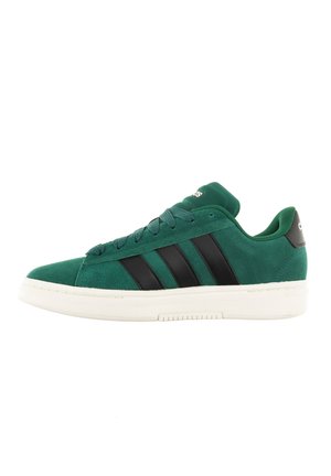 Zapatillas de ante verde con franjas de cuero negro. Suela de goma blanca, punta redondeada y cordones de tela texturizada. Diseño y marca minimalistas.