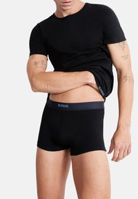 Svart bomull T-skjorte med korte ermer og rund hals, kombinert med svarte shorts-boxere med en blå SLOGGI midjebånd.
