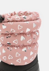 Der rosa Stiefel hat einen gerafften Schaft mit silbernen Herzmustern, einer schwarzen Gummisohle und einer glatten Stofftextur. Auffällige glänzende Akzente sind ebenfalls enthalten.