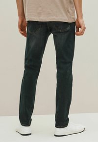 Mørkeblå skinny jeans lavet af denim, med en glat tekstur, standardlommer og et enkelt design. Paris med hvide sneakers.