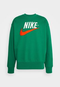 Grön sweatshirt med rund halsringning och vit "NIKE"-text samt en orange swoosh-logotyp på framsidan, med ribbad mudd och midja.
