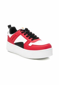 Zapatilla roja y blanca con detalles en negro, que cuenta con un cuello acolchado, suela gruesa blanca y cordones negros. Material sintético suave y punta redondeada.