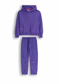 Fioletowy zestaw bluzy z kapturem i dresowych spodni. Bluza ma zamek z przodu, dwie boczne kieszenie i ściągacze na mankietach. Miękka tkanina, luźny krój, minimalne detale.