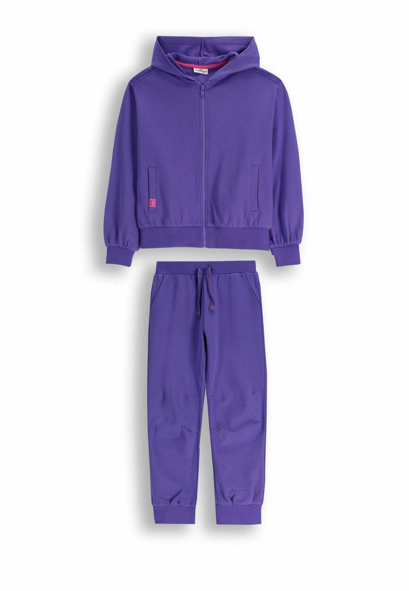 Fioletowy zestaw bluzy z kapturem i dresowych spodni. Bluza ma zamek z przodu, dwie boczne kieszenie i ściągacze na mankietach. Miękka tkanina, luźny krój, minimalne detale.