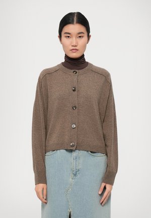 Brown knitted cardigan with a round neckline, long sleeves, and six large buttons down the front, paired with a light blue denim skirt.