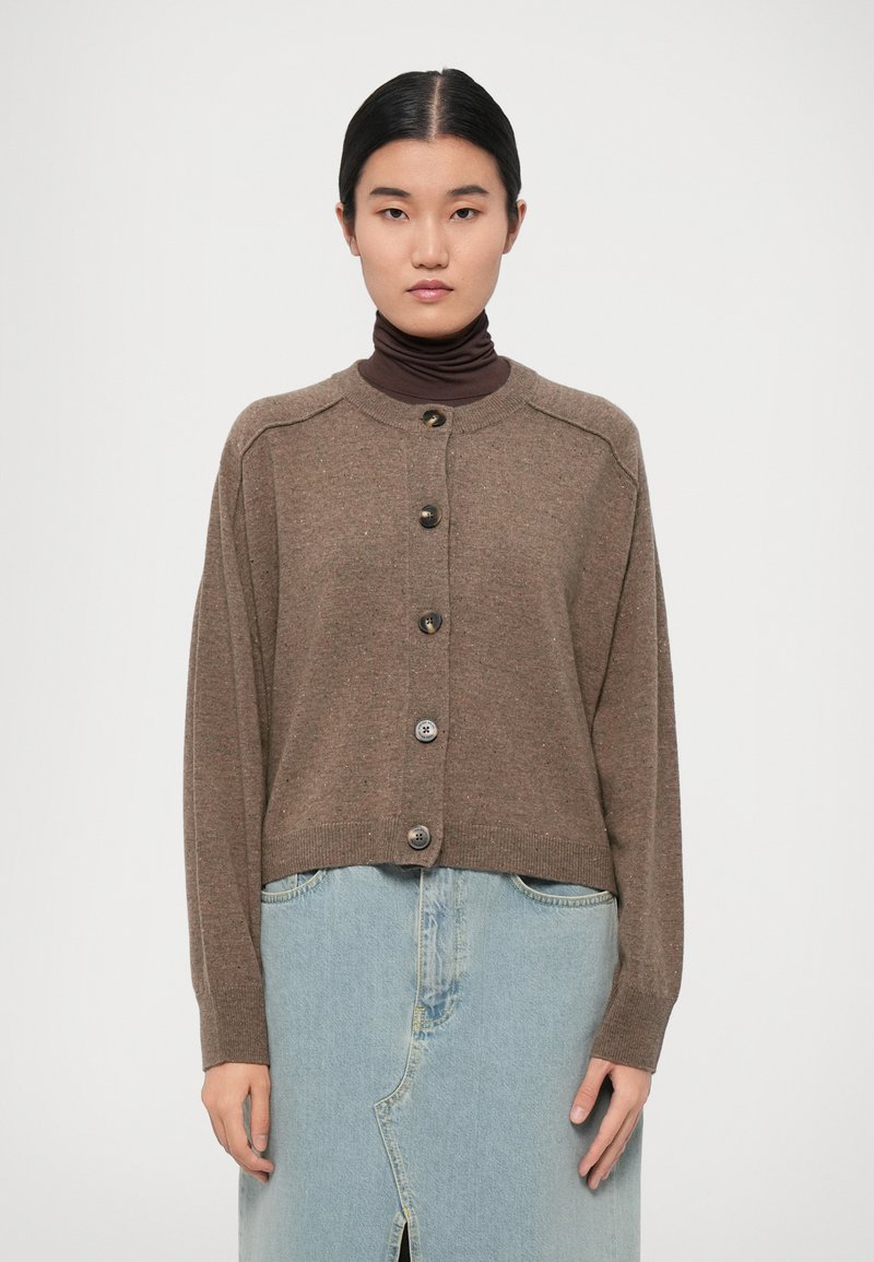 Brown knitted cardigan with a round neckline, long sleeves, and six large buttons down the front, paired with a light blue denim skirt.