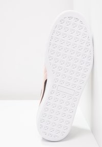 Semelle en caoutchouc blanche avec motif géométrique texturé, dessus en daim rose clair avec accents noirs, design épuré.