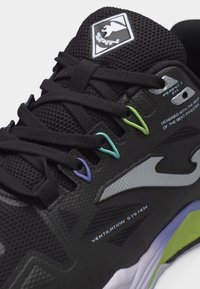 Μαύρο αθλητικό παπούτσι με δίχτυ στο πάνω μέρος, μαύρα κορδόνια περασμένα από πολύχρωμες θηλιές, και κείμενο επωνυμίας που περιλαμβάνει «Σύστημα Αερισμού» και «Τέλεια Προσαρμογή».