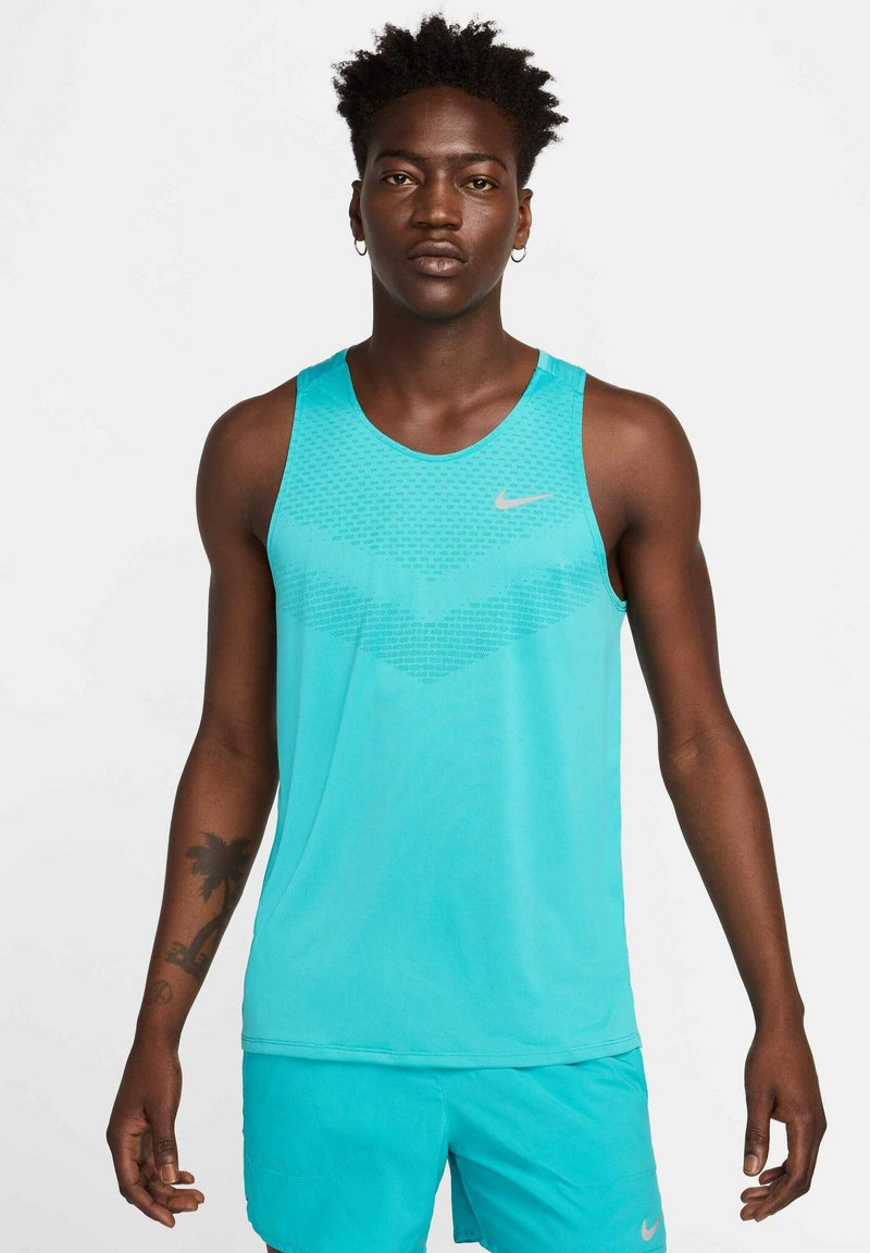Débardeur Nike bleu clair avec motif texturé, col rond et logo. Tissu lisse avec une coupe décontractée, idéal pour les vêtements de sport.