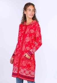 Roter, floral gemusterter Kapuzenmantel mit vollem Frontreißverschluss, zwei Taschen und detaillierten blauen Akzenten an Ärmeln und Saum. Weicher Stoff.