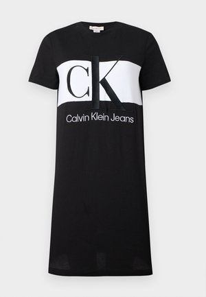 Zwarte jurk met korte mouwen en een witte horizontale band met grote letters "CK" en daaronder de tekst "Calvin Klein Jeans".