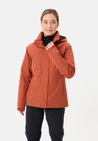 Giacca resistente all'acqua di colore ruggine, con chiusura frontale a zip e cappuccio regolabile, maniche lunghe e una texture liscia e opaca.