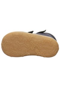 Helle Gummisohle mit strukturiertem Grip-Muster, ausgestattet mit einem dunklen Obermaterial und verstellbarem Riemen. Entwickelt für Stabilität und Traktion.
